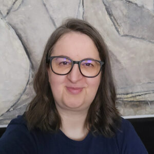 Annette Schwindt mit langen Haaren und Brille lächelt in die Kamera