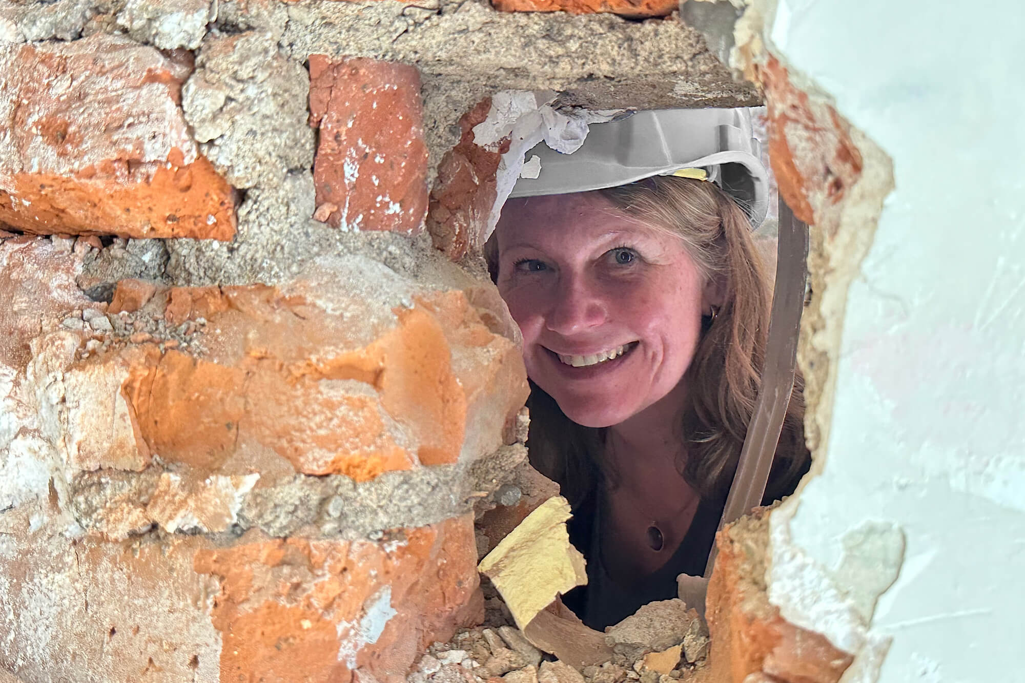 Architektin Dorothea Kaleschke-Weingarten schaut durch ein Loch in euner Mauer